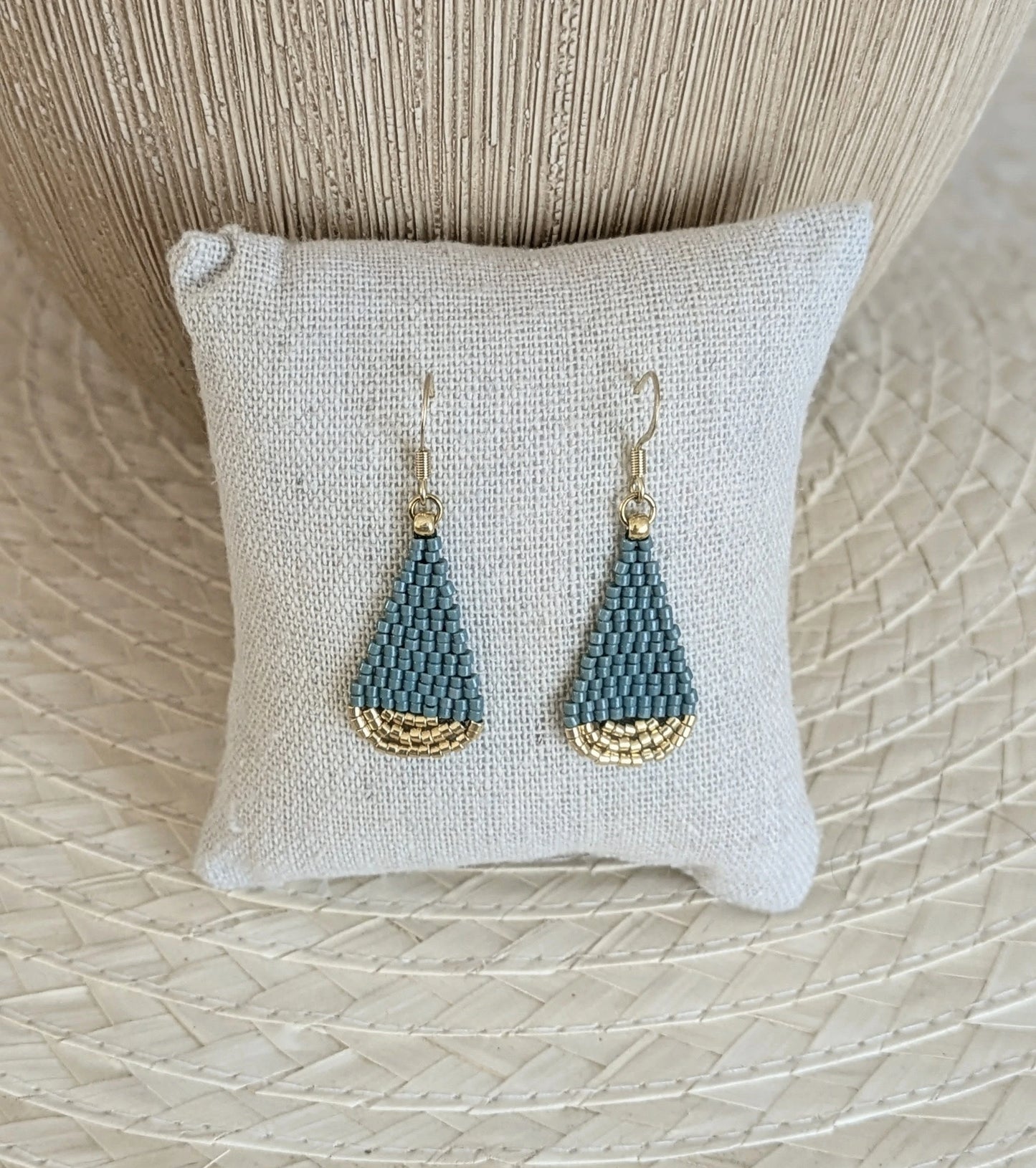 Boucles artisanales forme goutte couleur bleu vert disposées sur un coussin de présentation- Décor bohème.