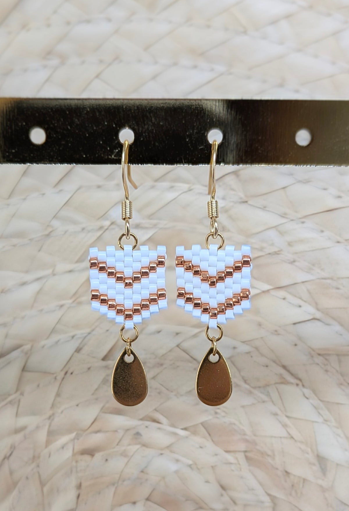 Gros plan sur les boucles tissées main en perles miyuki blanches et cuivrées