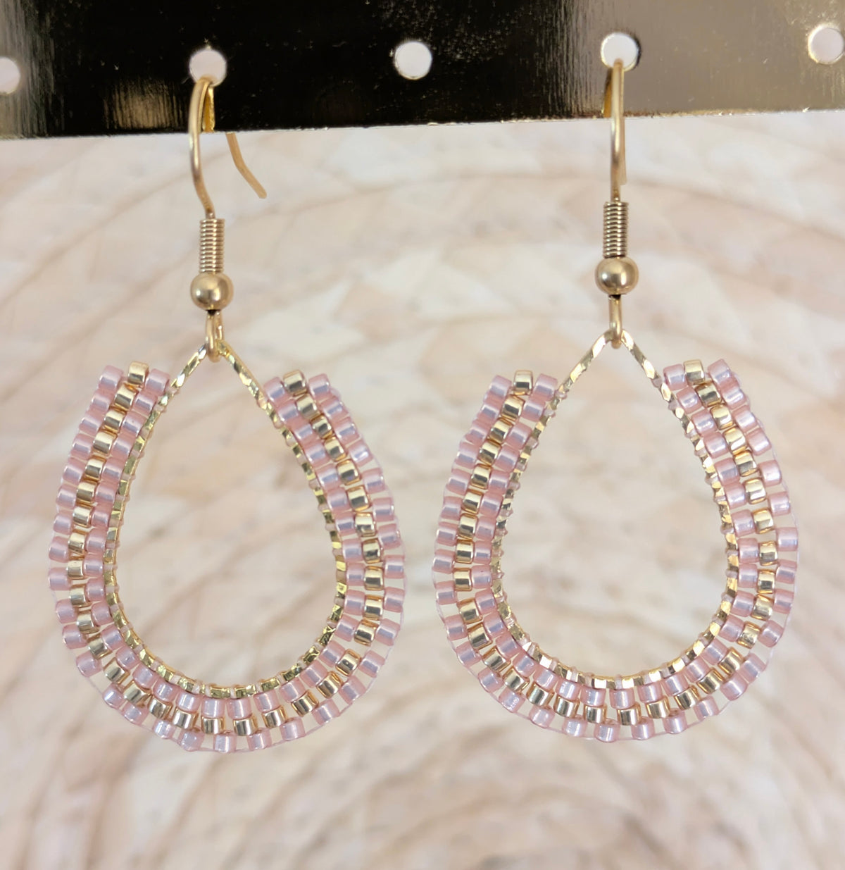 Boucles d'oreilles artisanales en perles tissées beiges. Gros plan sur le tissage.
