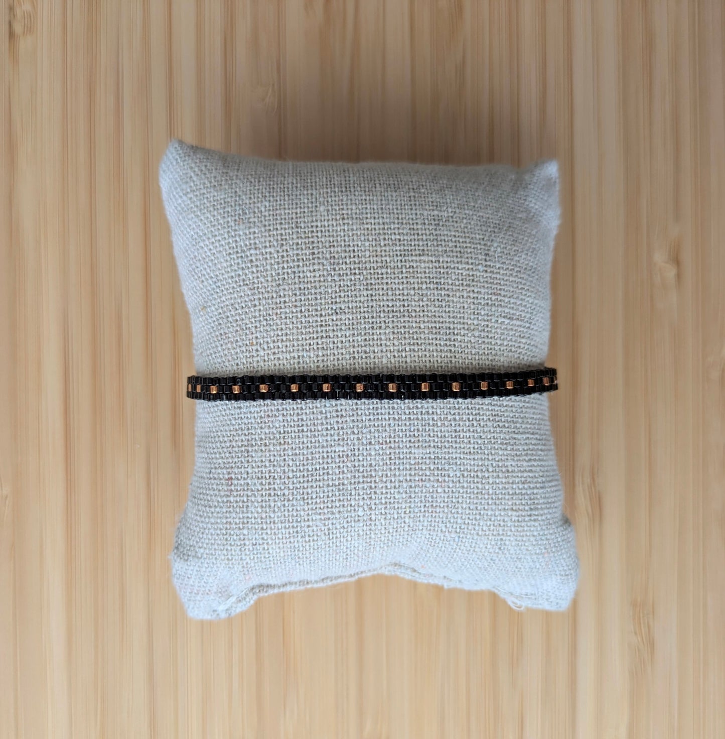 Bracelet artisanal en perles de verre noires sur un coussin