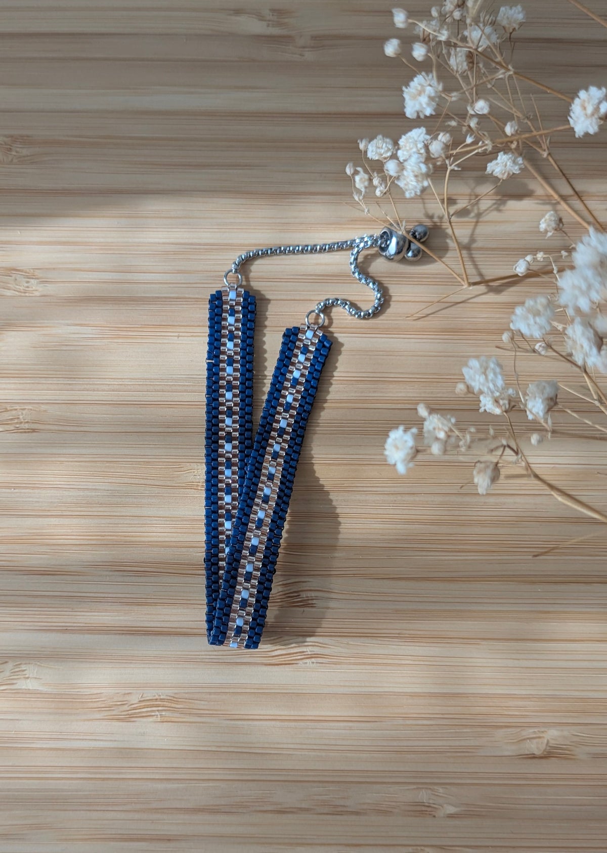 Bracelet en perles bleues posé sur un meuble en bois clair