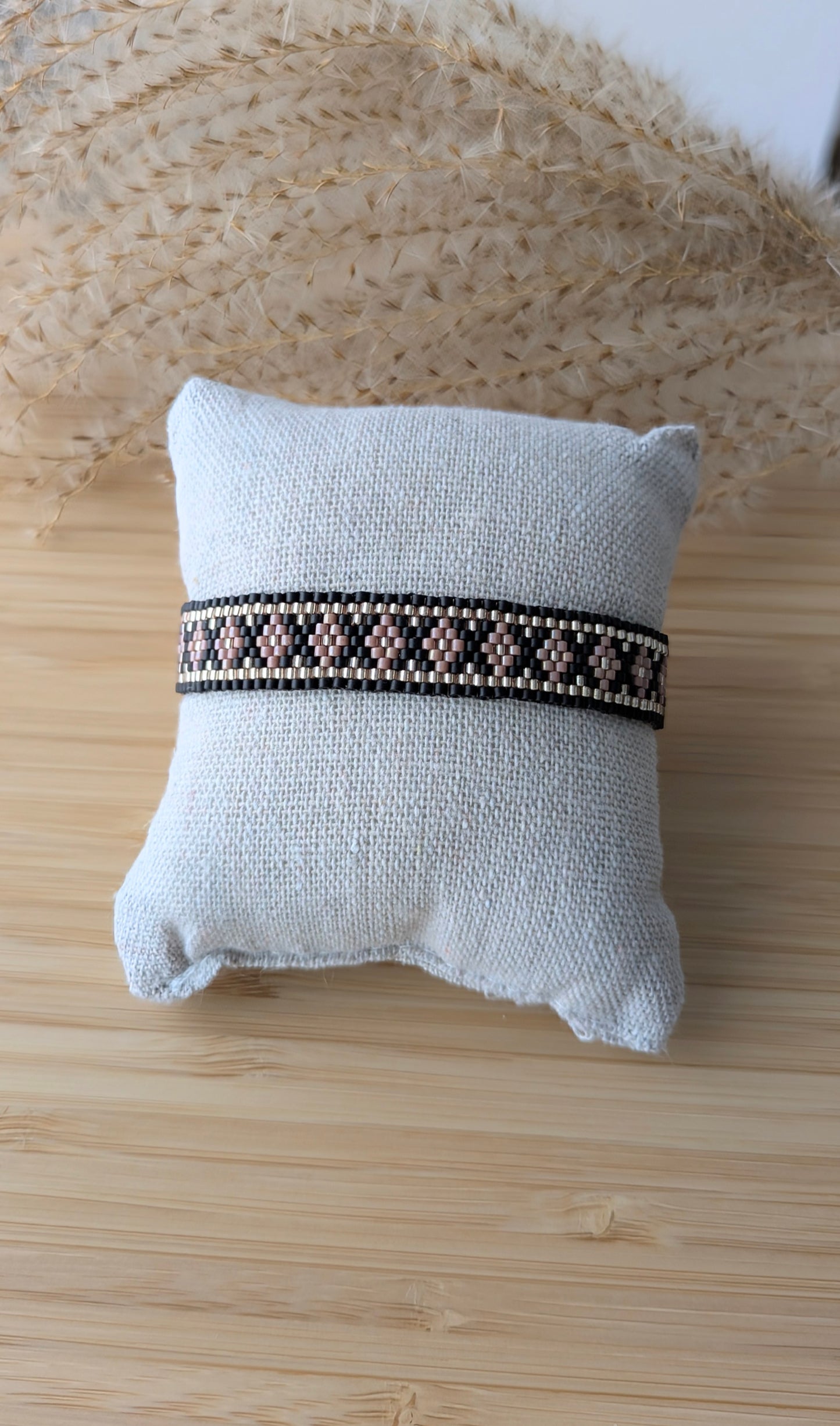 Bracelet tissage peyote en perles miyuki roses et noires présenté sur un coussin