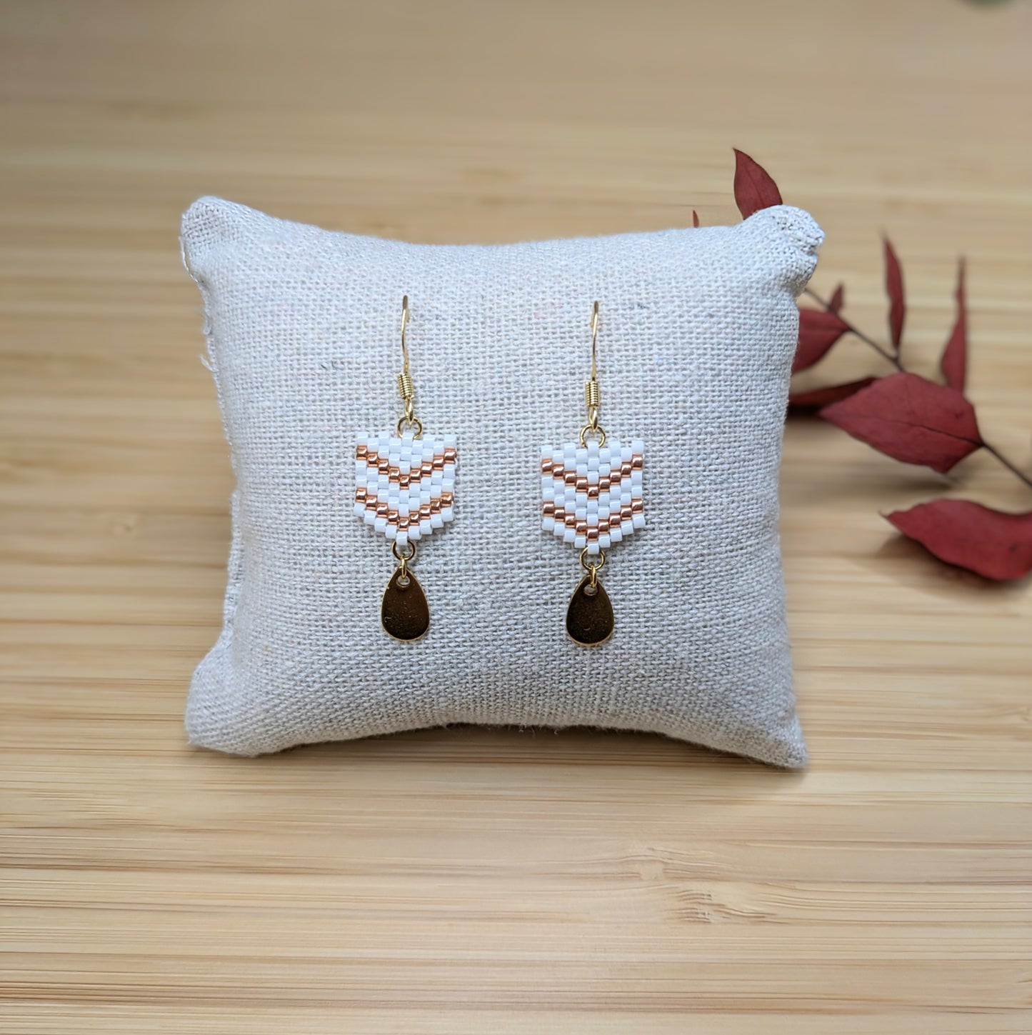 Boucles d'oreilles faites main en perles blanches sur un coussin