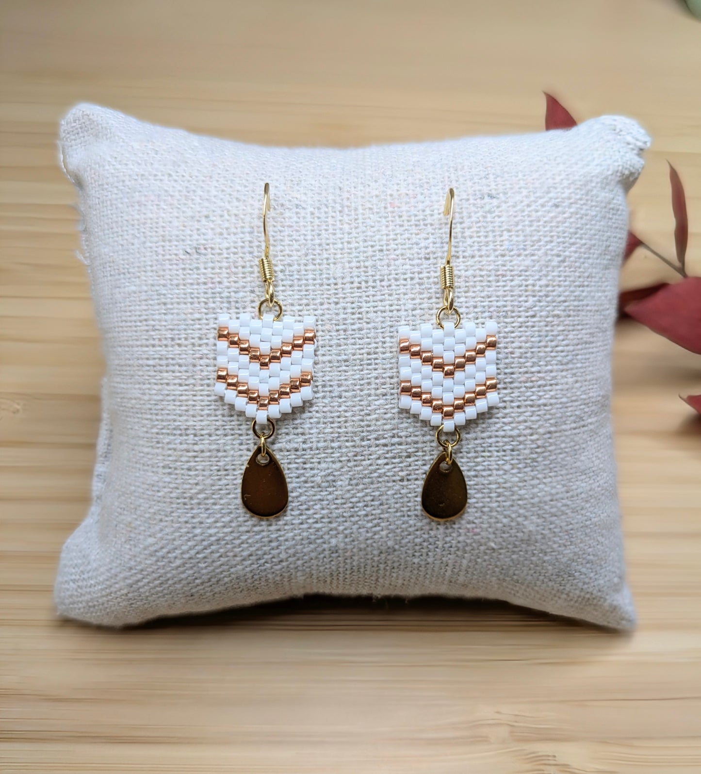 Boucles d'oreilles pendantes en perles blanches présentées sur un coussin