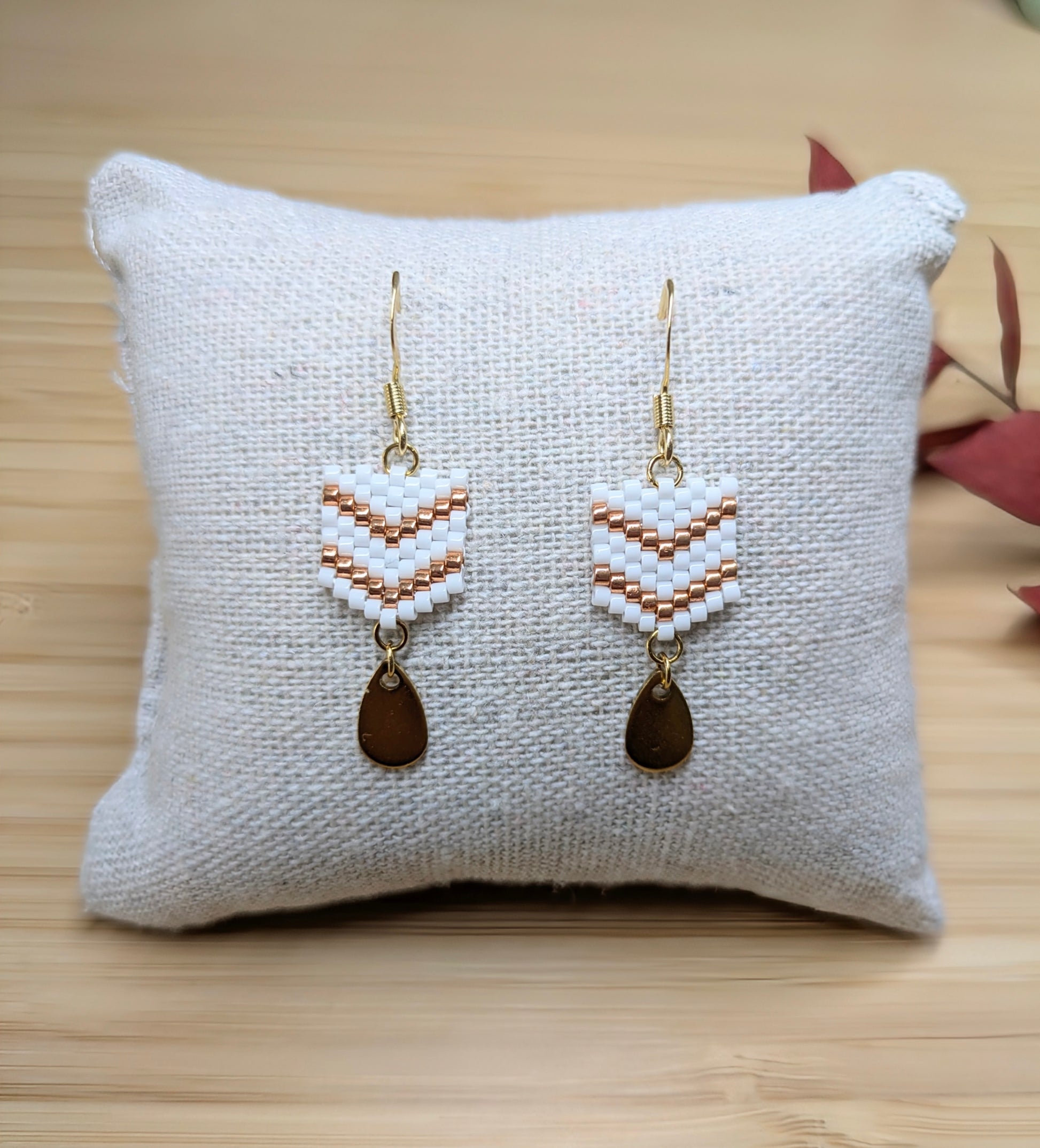 Boucles d'oreilles pendantes en perles blanches présentées sur un coussin