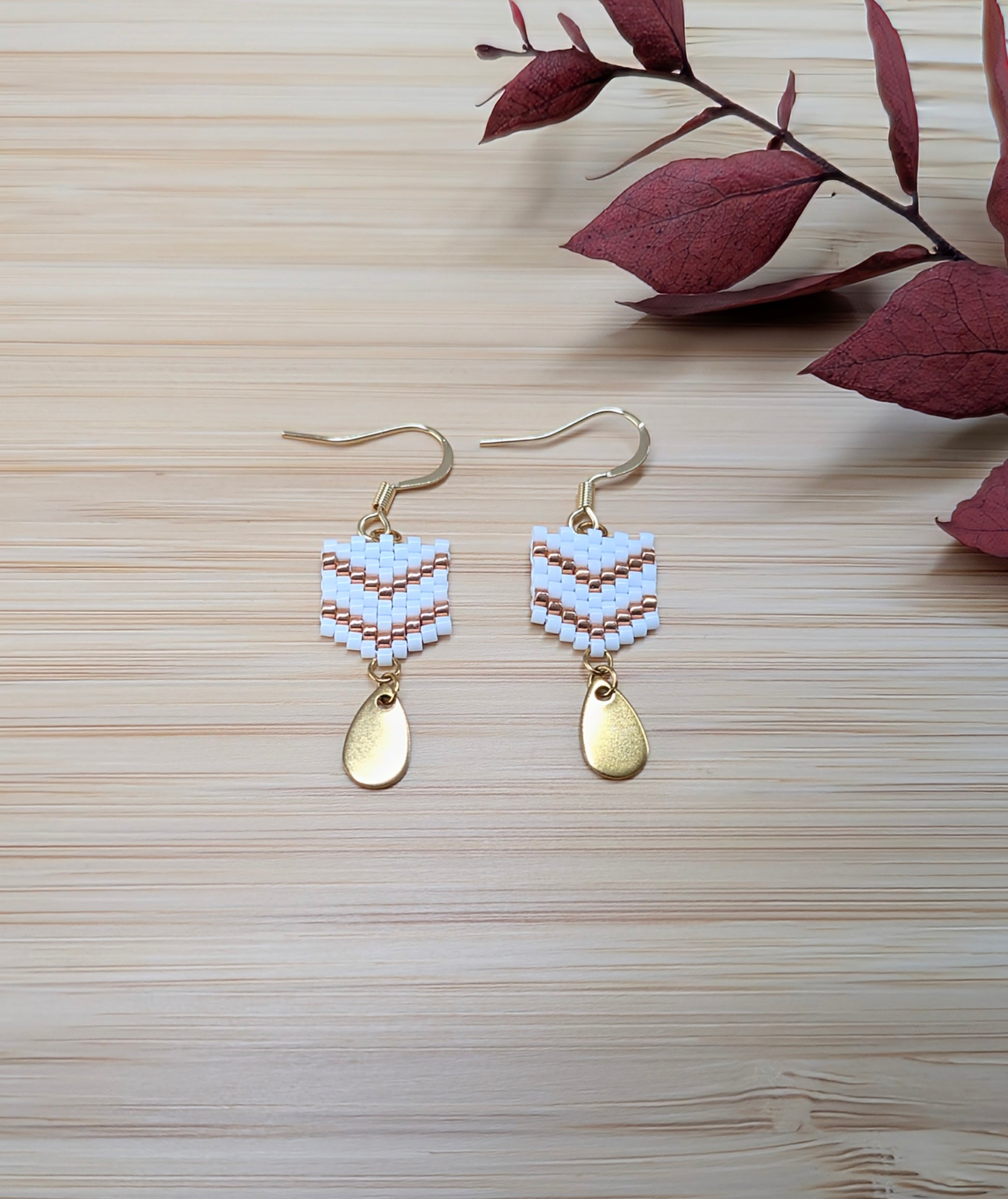 Boucles d'oreilles artisanales présentées à plat sur du bambou