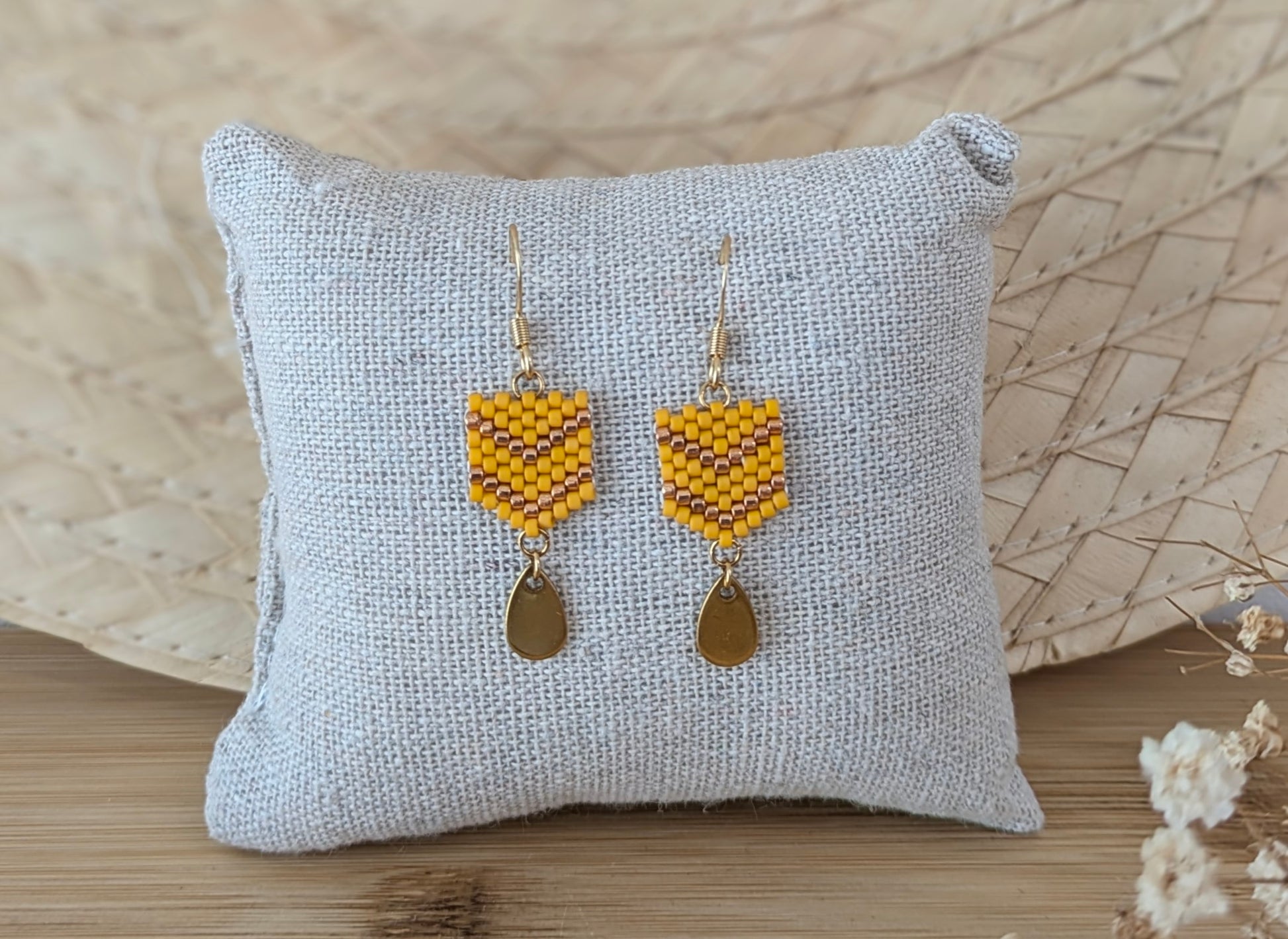 Boucles d'oreilles perles miyuki jaunes présentées sur coussin dans un décor bohème