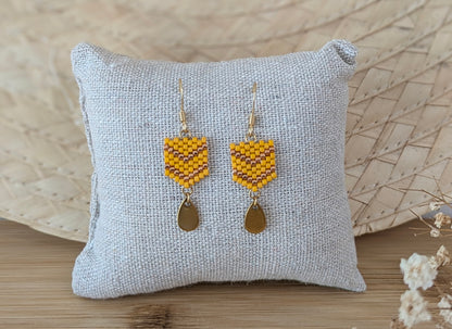 Boucles d'oreilles perles miyuki jaunes présentées sur coussin dans un décor bohème