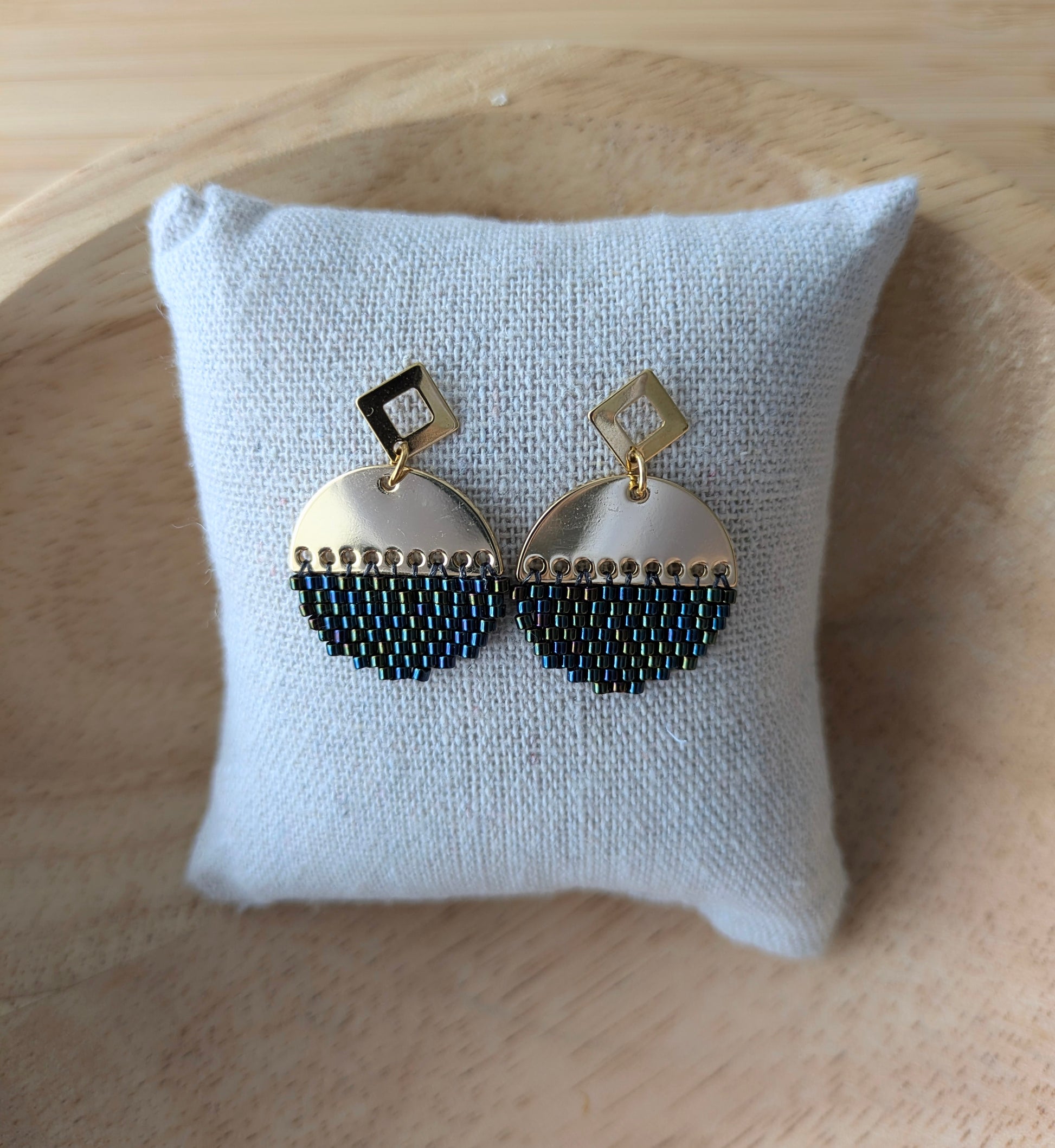 Boucles d'oreilles rondes en perles tissées sur connecteur demi-lune doré présentées sur un coussin