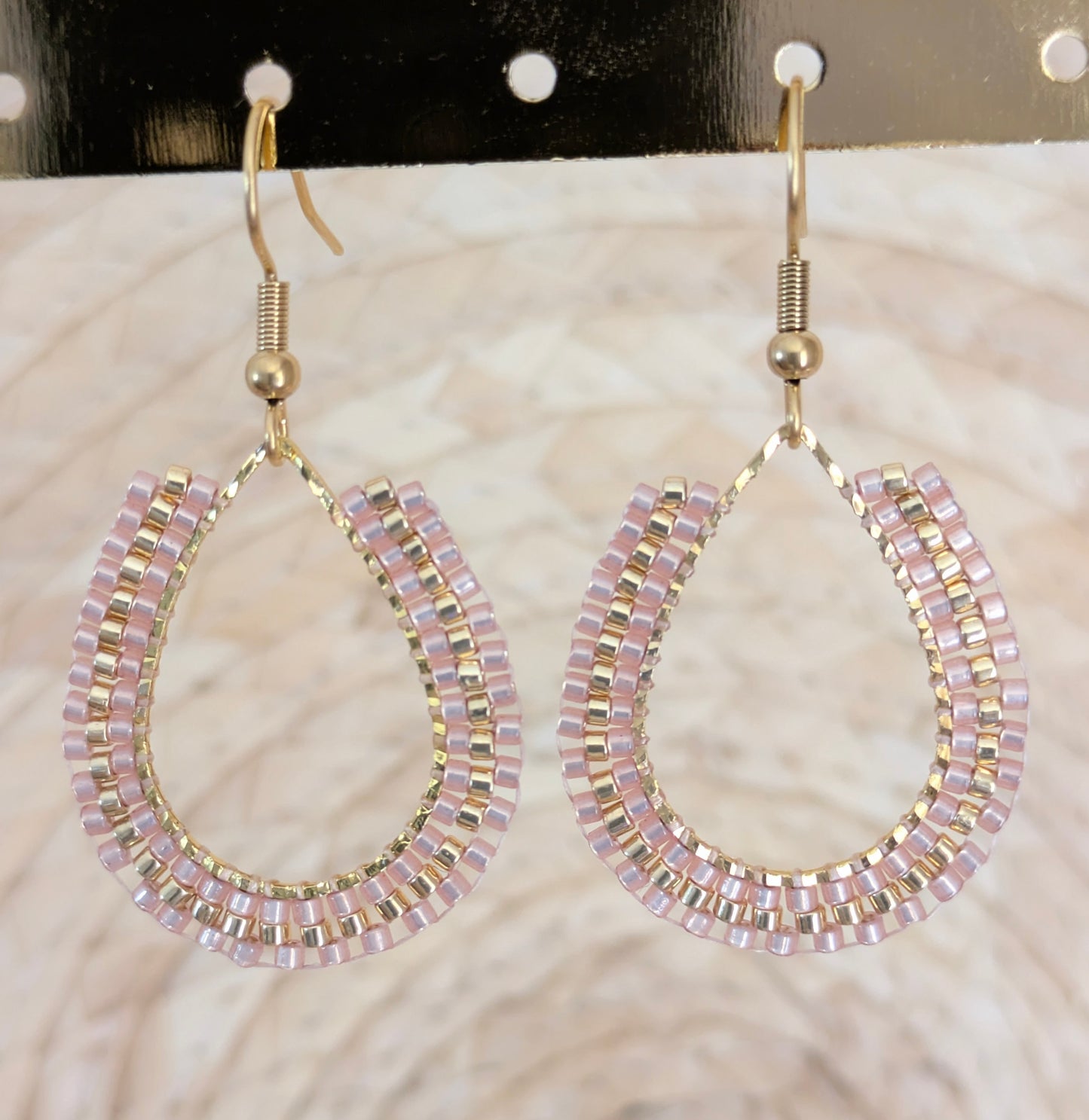 Boucles d'oreilles artisanales en perles tissées beiges. Gros plan sur le tissage.