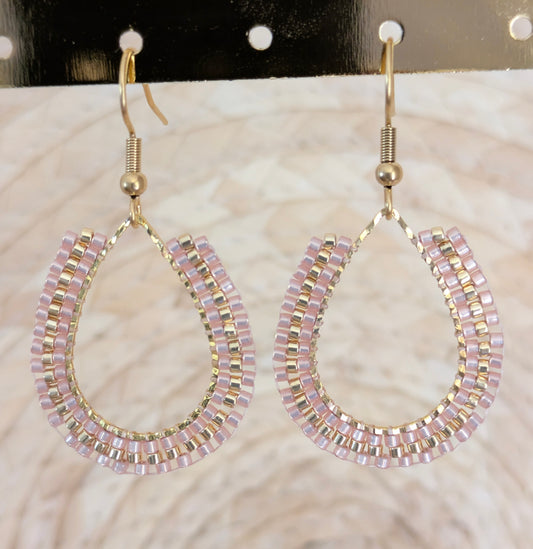 Boucles d'oreilles artisanales en perles tissées beiges. Gros plan sur le tissage.