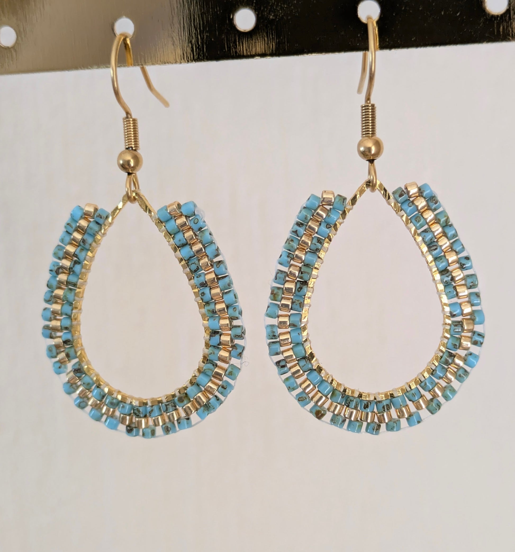 Boucles d'oreilles en perles bleues tissées sur anneau forme goutte. Gros plan sur tissage en brickstitch.