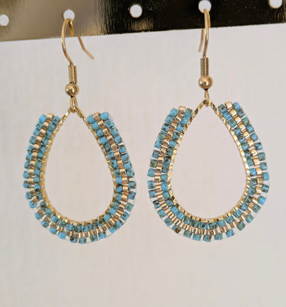Boucles d'oreilles en perles bleues tissées sur anneau forme goutte. Gros plan sur tissage en brickstitch.