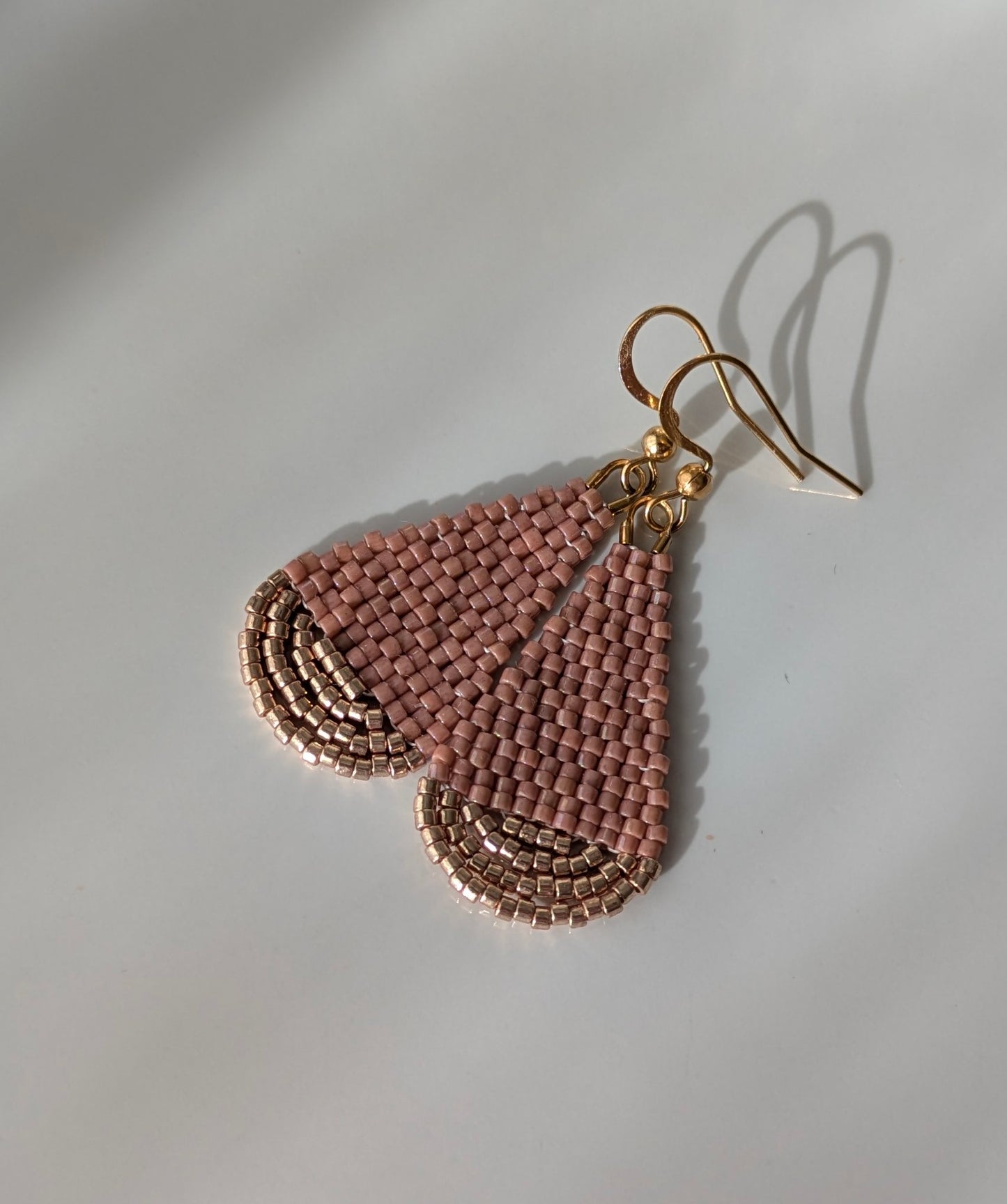 Gros plan sur le tissage artisanal des boucles goutte en perles Miyuki roses