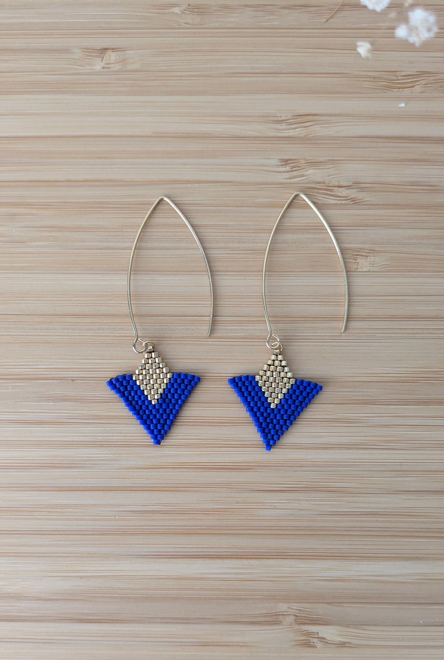 Vue détaillée des boucles artisanales bleues et dorées à plat sur du bois