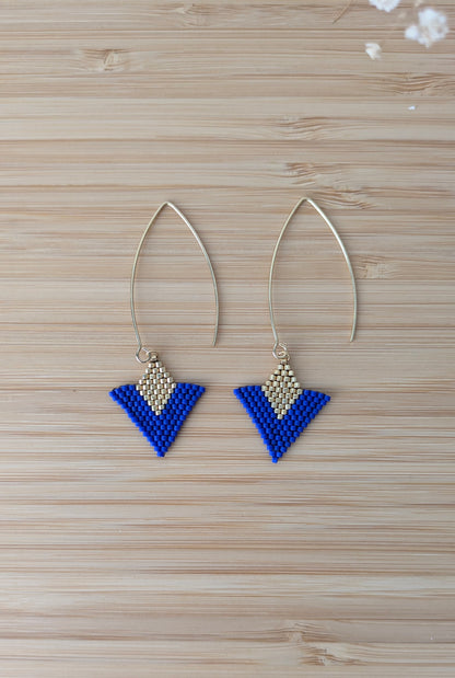 Vue détaillée des boucles artisanales bleues et dorées à plat sur du bois