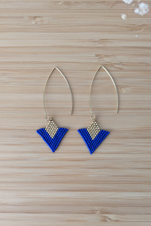 Vue détaillée des boucles artisanales bleues et dorées à plat sur du bois