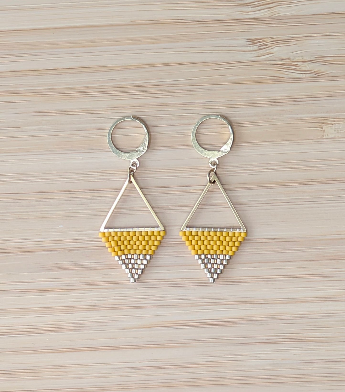 Boucles pendantes en perles tissées jaunes et dorées sur triangle en acier inoxydable doré.