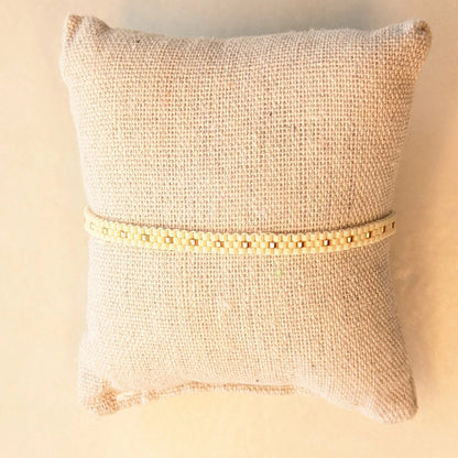 Bracelet tissé fin crème présenté sur coussin