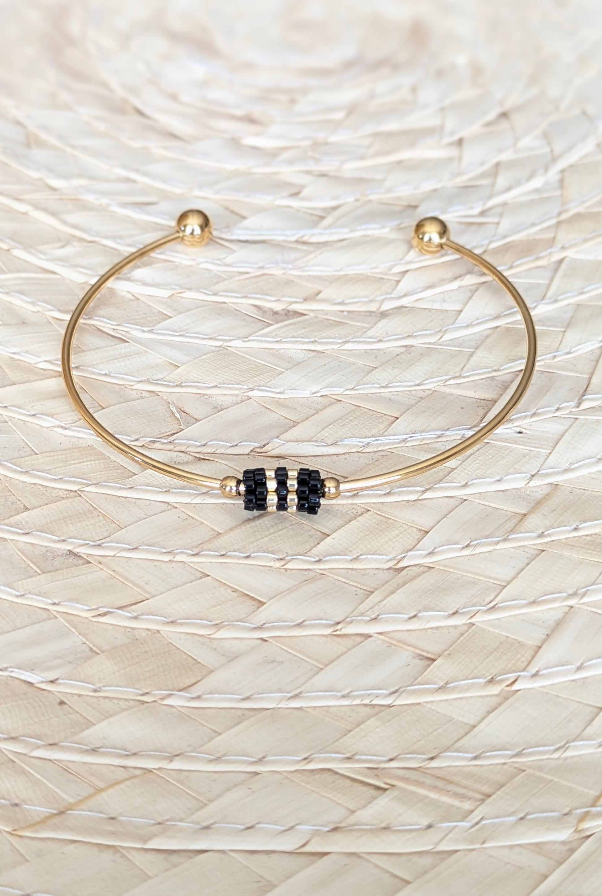 Bracelet jonc doré avec tissage de perles noires- Présenté à plat-