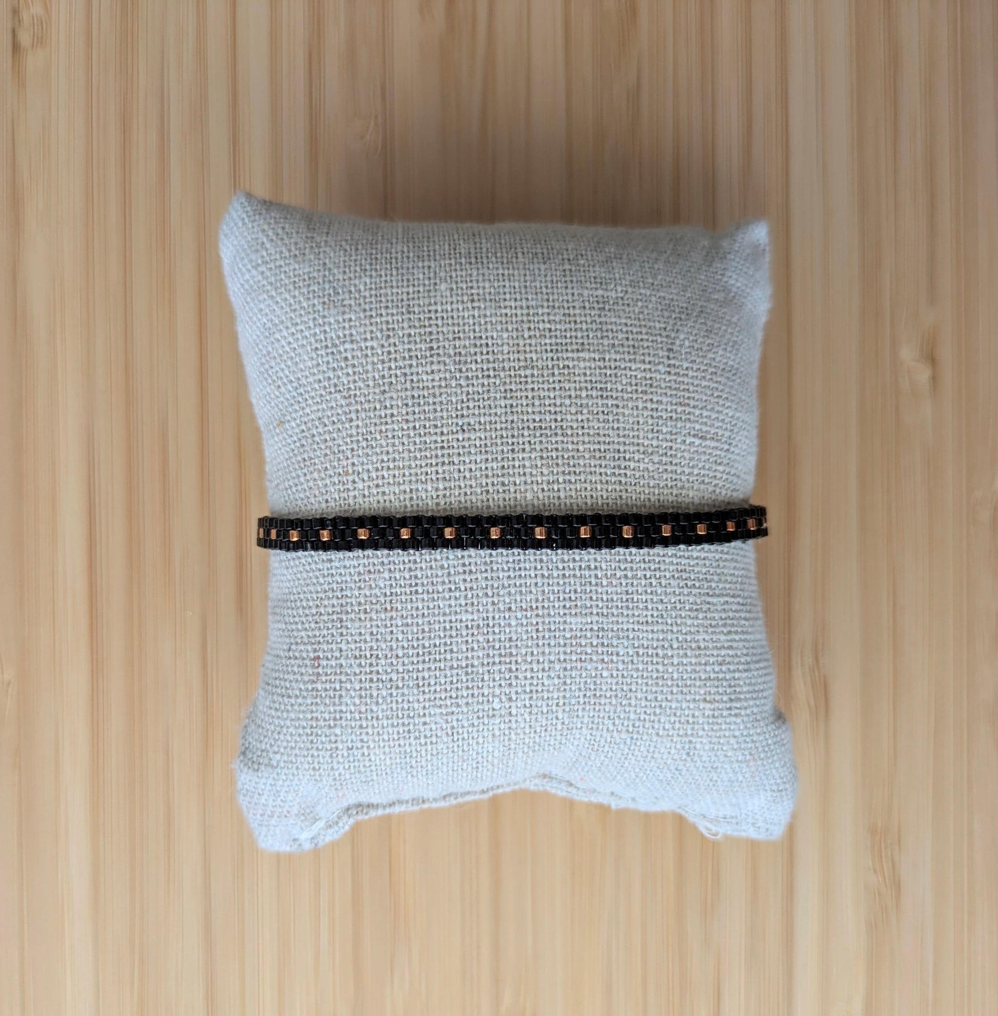 Bracelet artisanal en perles de verre noires sur un coussin