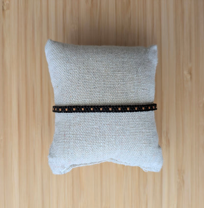 Bracelet artisanal en perles de verre noires sur un coussin