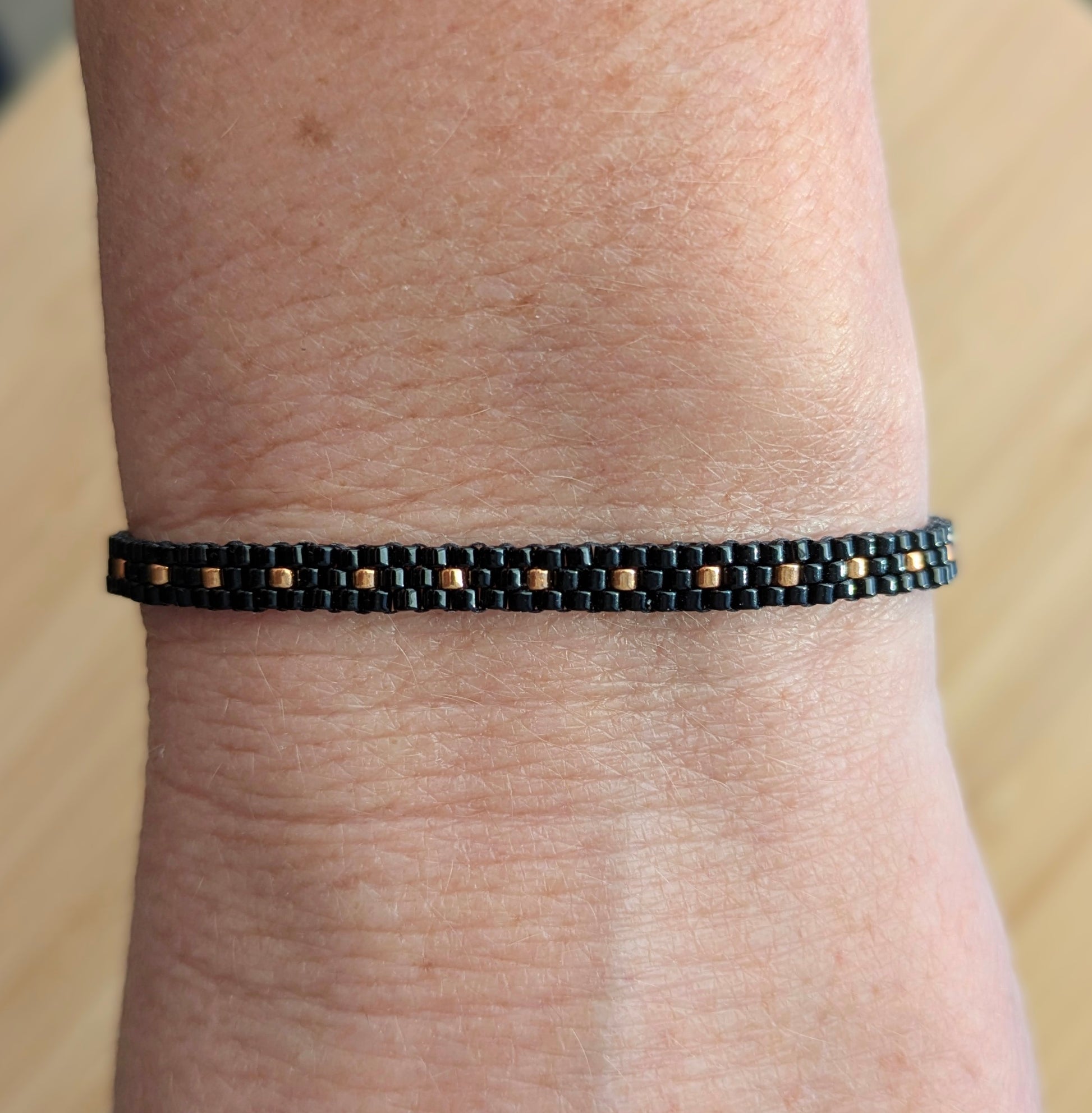 Bracelet fin en perles miyuki noires et cuivrées- Vue porté sur poignet femme