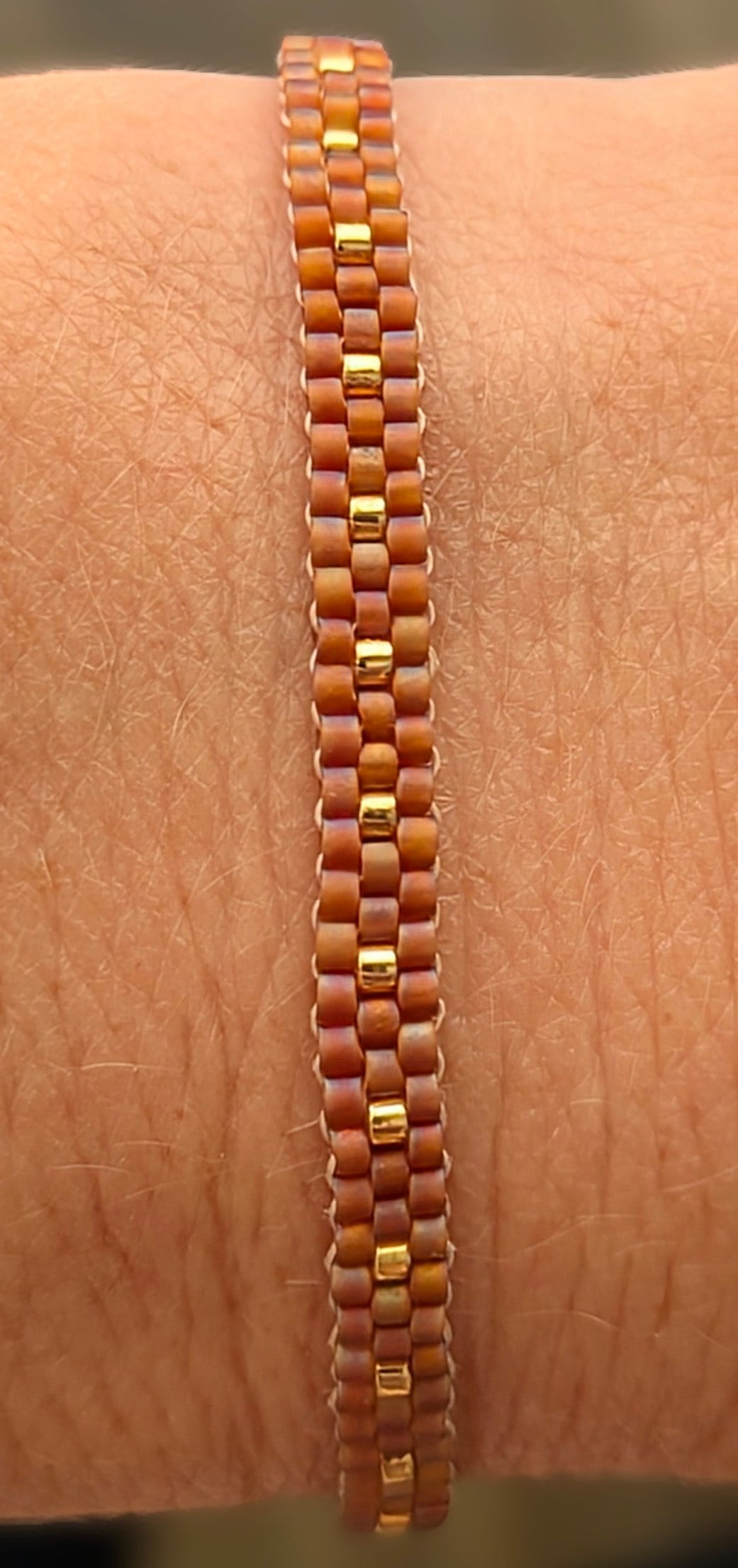 Bracelet fait main porté avec vue détaillée des perles rouges et dorées