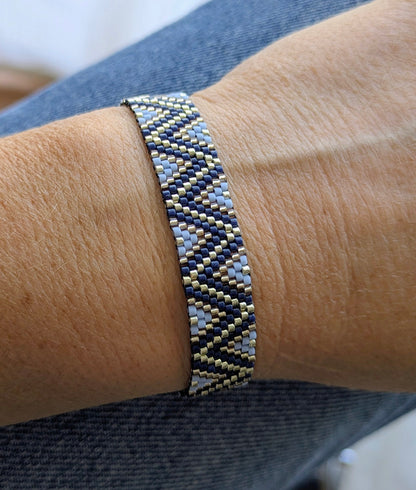 Bracelet tissé en perles miyuki bleues et argentées motifs zig zag sur un poignet de femme. Bijou fait main en gironde.