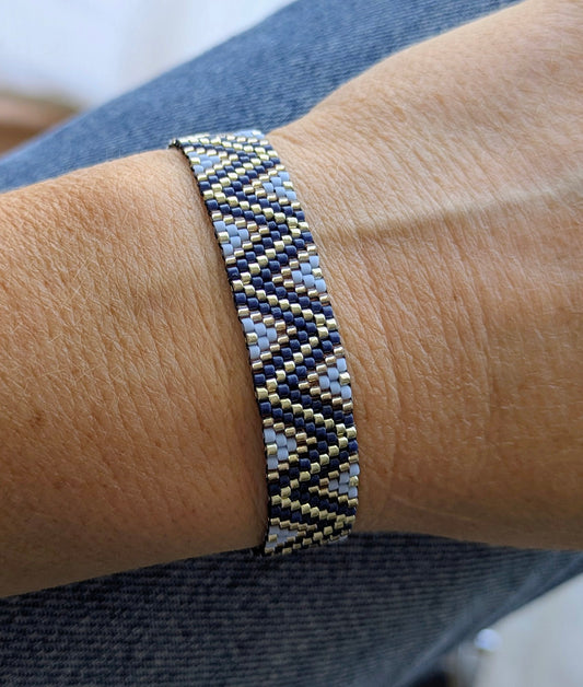 Bracelet tissé en perles miyuki bleues et argentées motifs zig zag sur un poignet de femme. Bijou fait main en gironde.