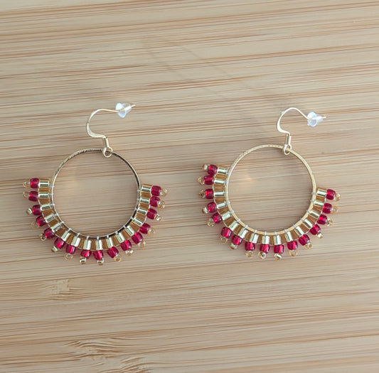 Créoles en perles tissées rouges et dorées vues de haut sur bois