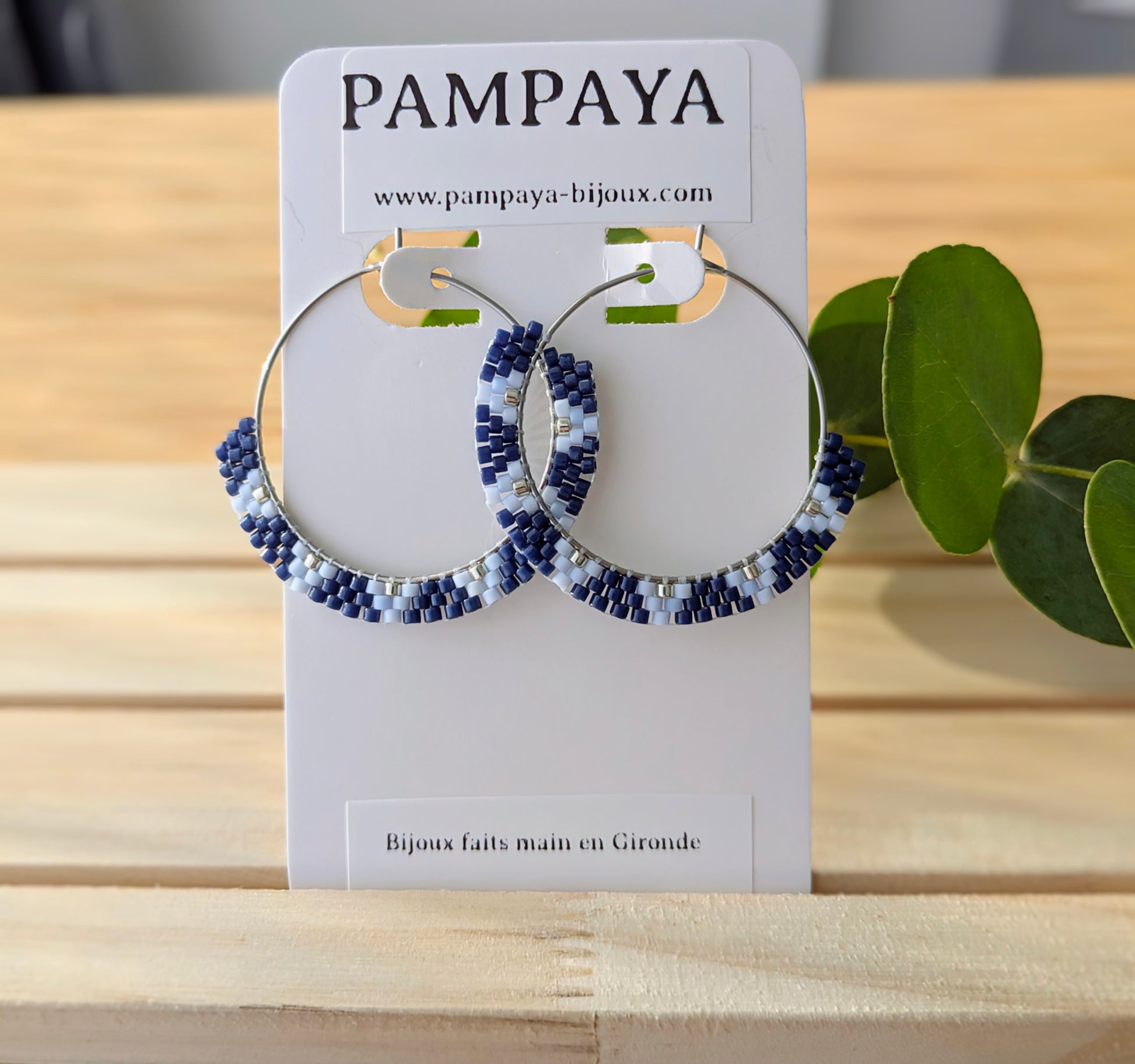 Créoles en perles bleues présentées sur carton à bijoux avec inscription " Pampaya- bijoux faits main en Gironde"