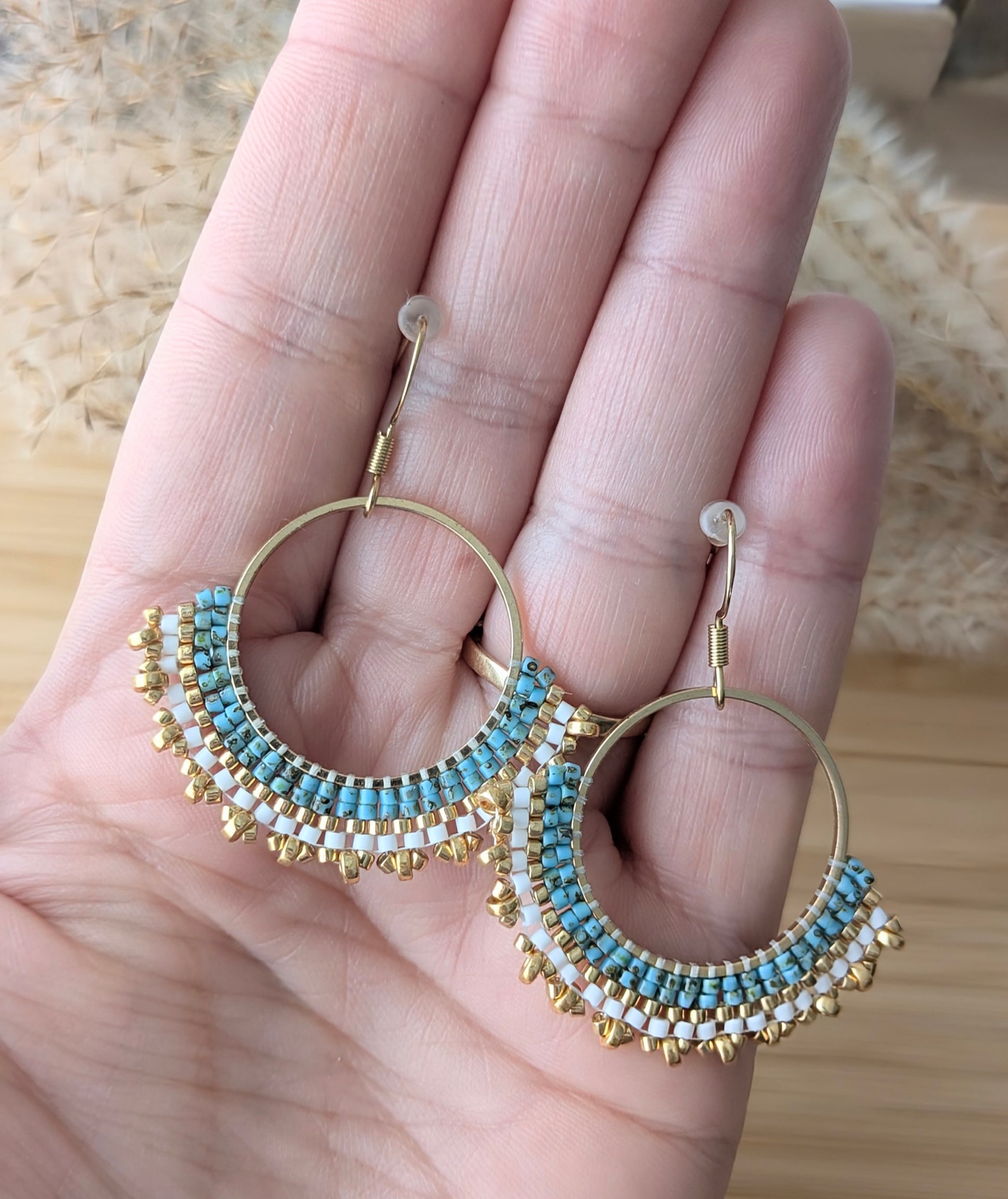 Vue de la taille des créoles tissées main en perles miyuki bleues et dorées présentées sur une main de femme