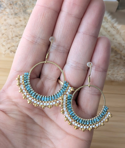 Vue de la taille des créoles tissées main en perles miyuki bleues et dorées présentées sur une main de femme