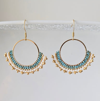 Vue détaillée du tissage artisanal des créoles pendantes en perles de verre bleues et dorées