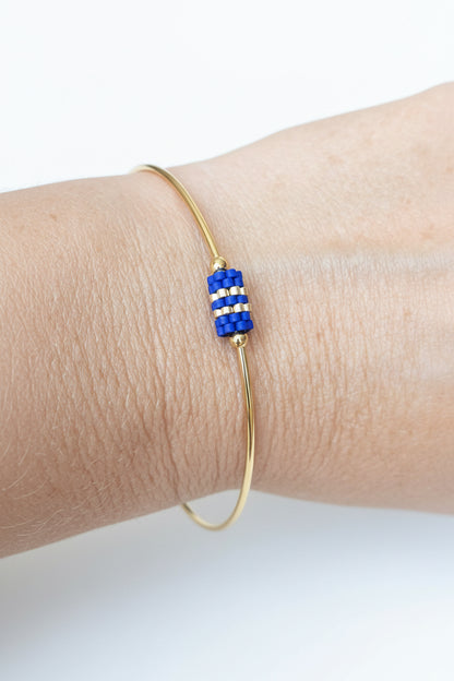 Jonc doré avec perles tissées bleues - Porté sur poignet féminin