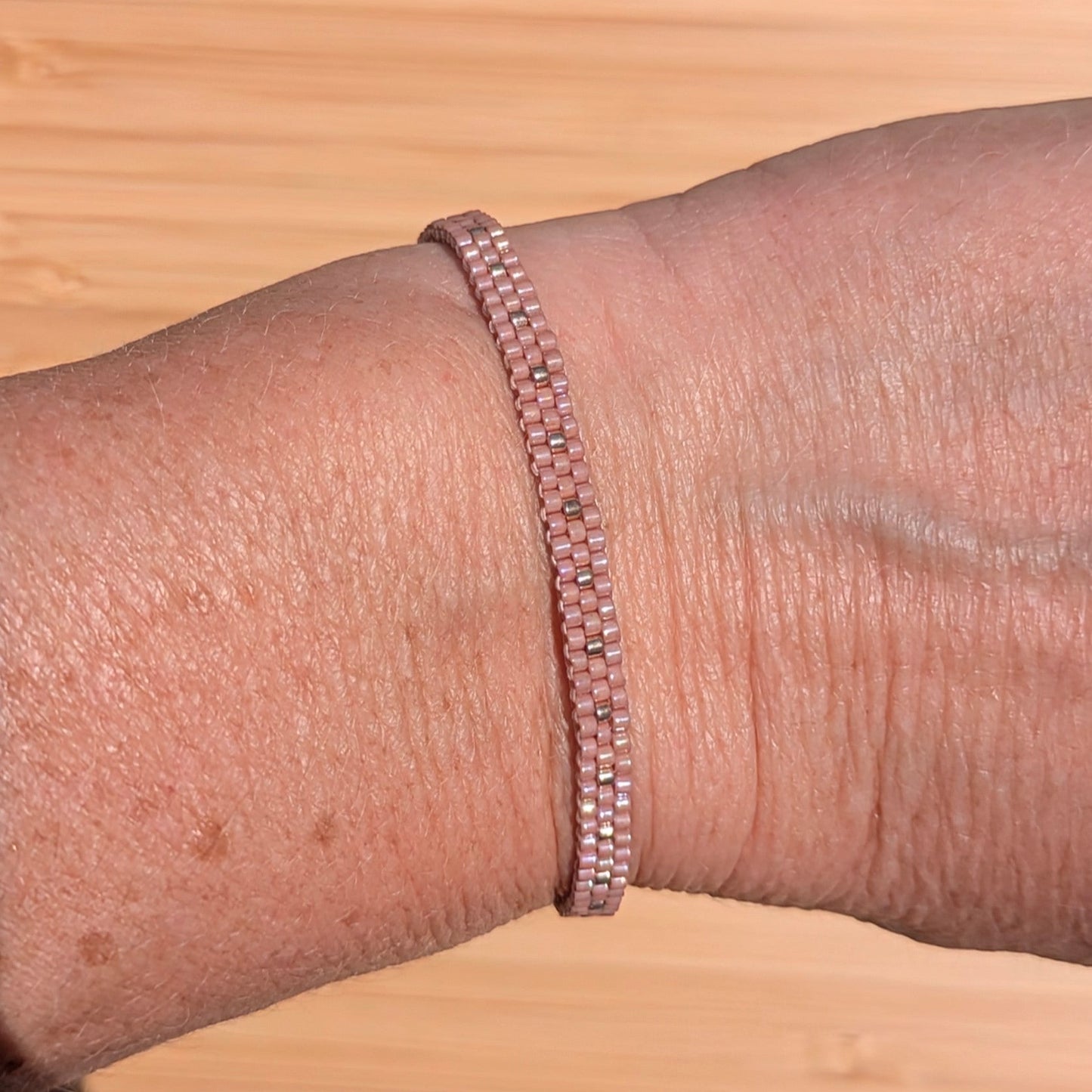 bracelet rose en perles tissées sur un poignet de femme