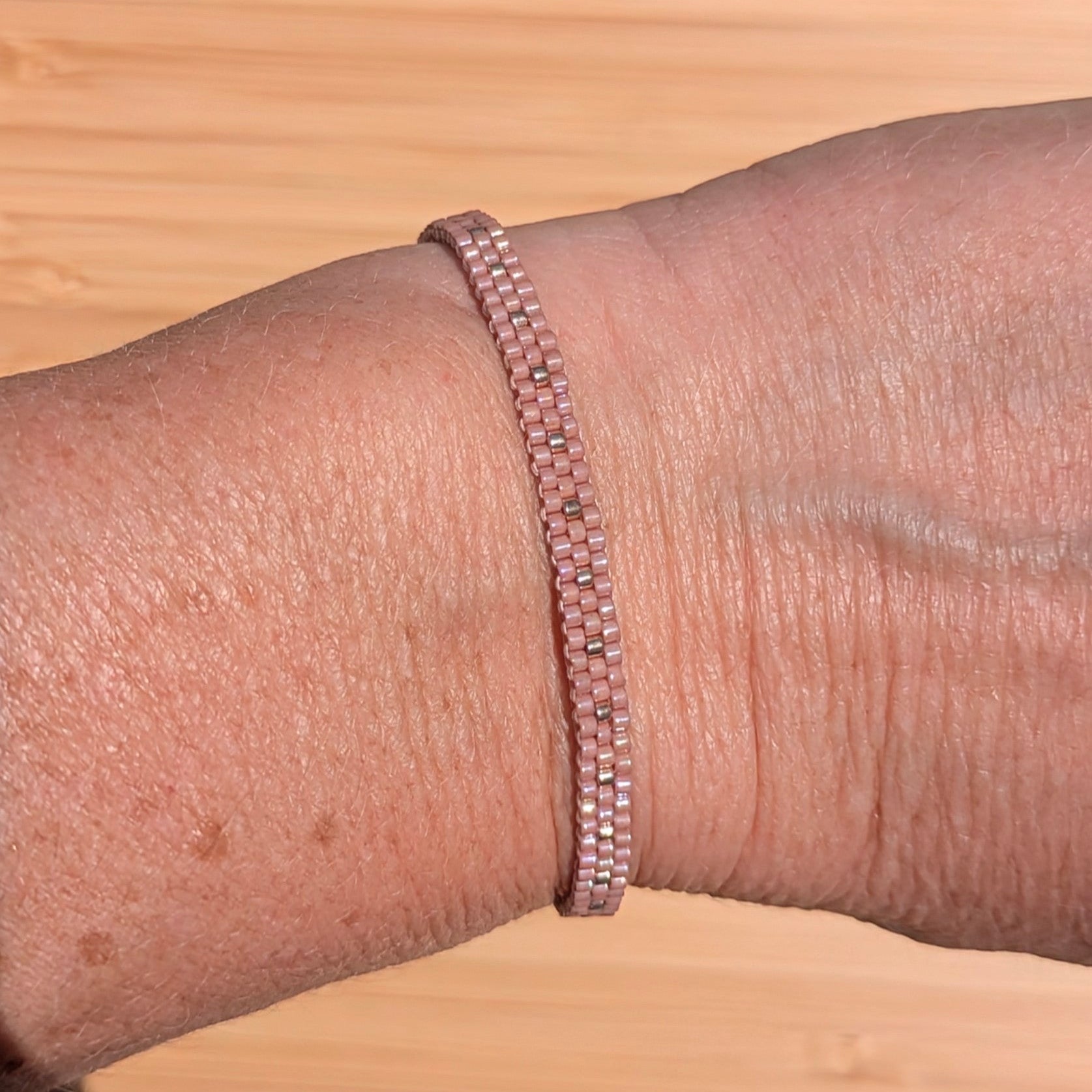 bracelet rose en perles tissées sur un poignet de femme