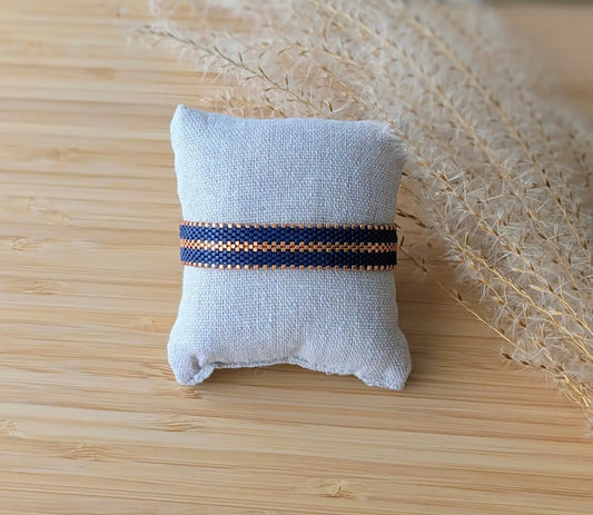 Bracelet artisanal en perles bleu marine présenté sur un coussin