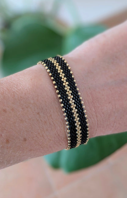 bracelet tissé main en perles miyuki noires et dorées porté sur poignet féminin