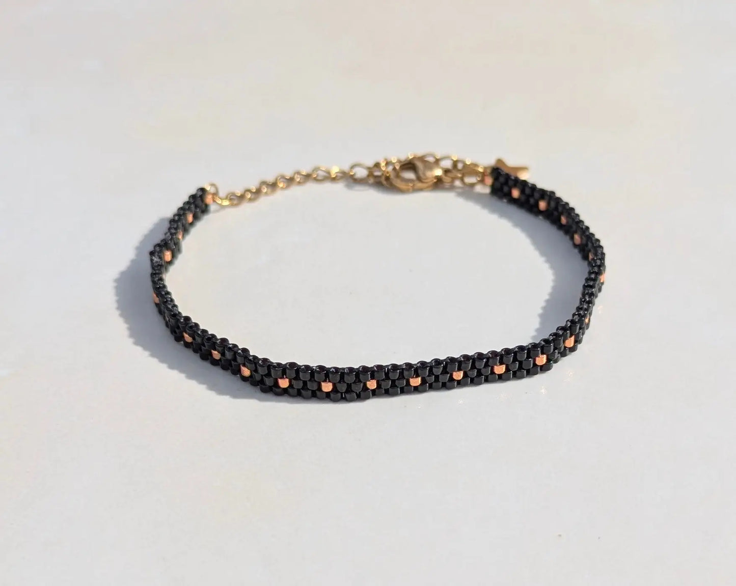 Vue d'ensemble du bracelet tissé fin en perles miyuki noires et acier inoxydable doré