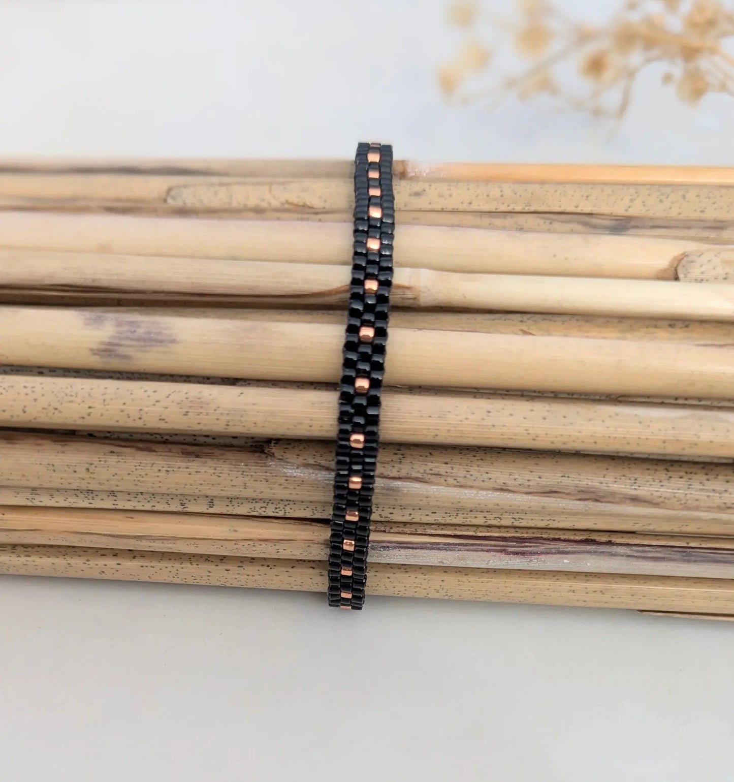 Bracelet tissé fin noir en perles de verre présenté sur bambous- Bijou bohème