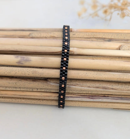 Bracelet tissé fin noir en perles de verre présenté sur bambous- Bijou bohème